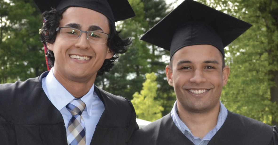 two male graduates smile at camera