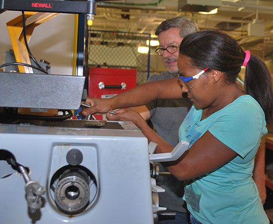 male instructor helps female student on machine