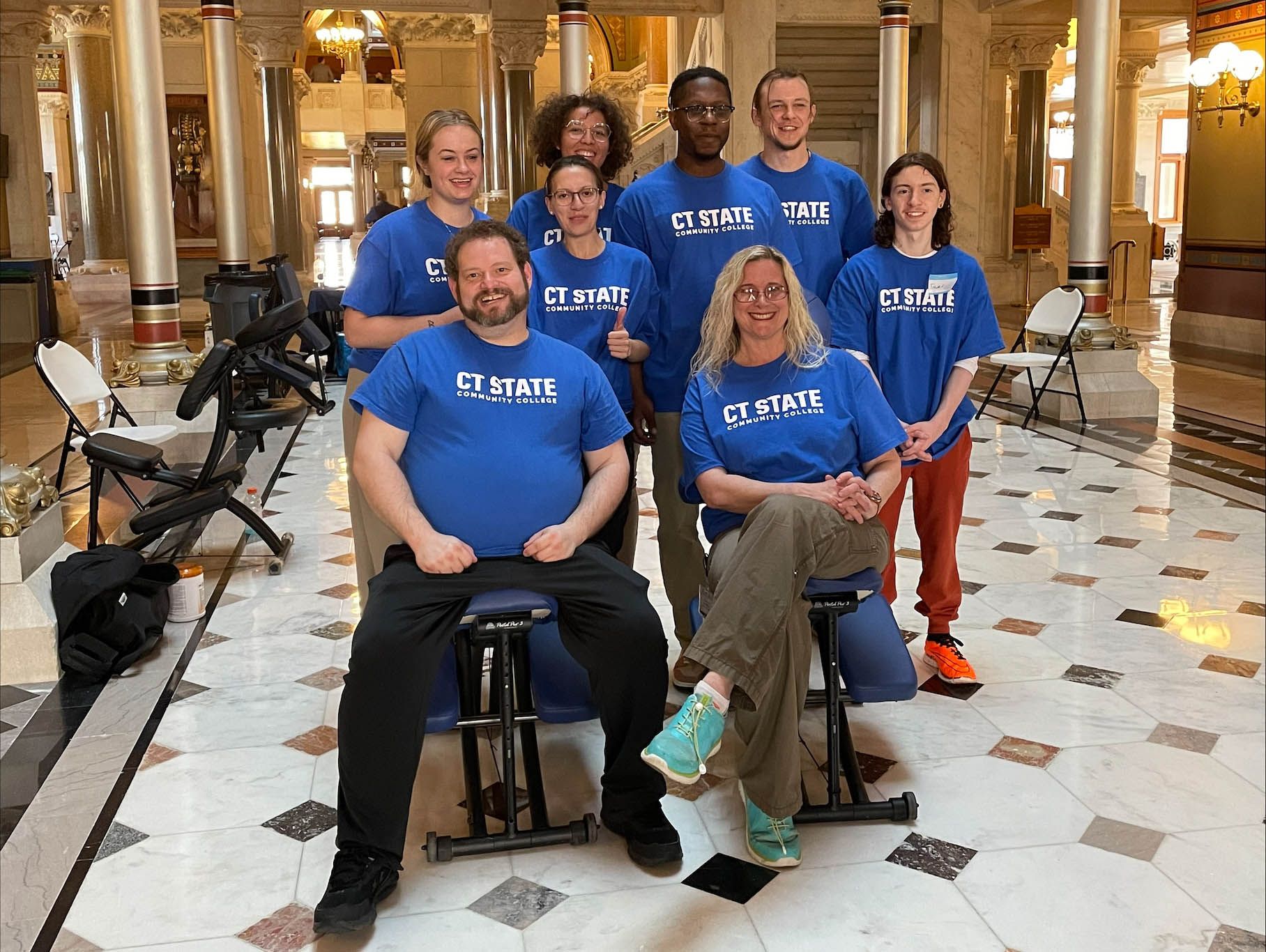 group of seven massage therapy students stand around massage table