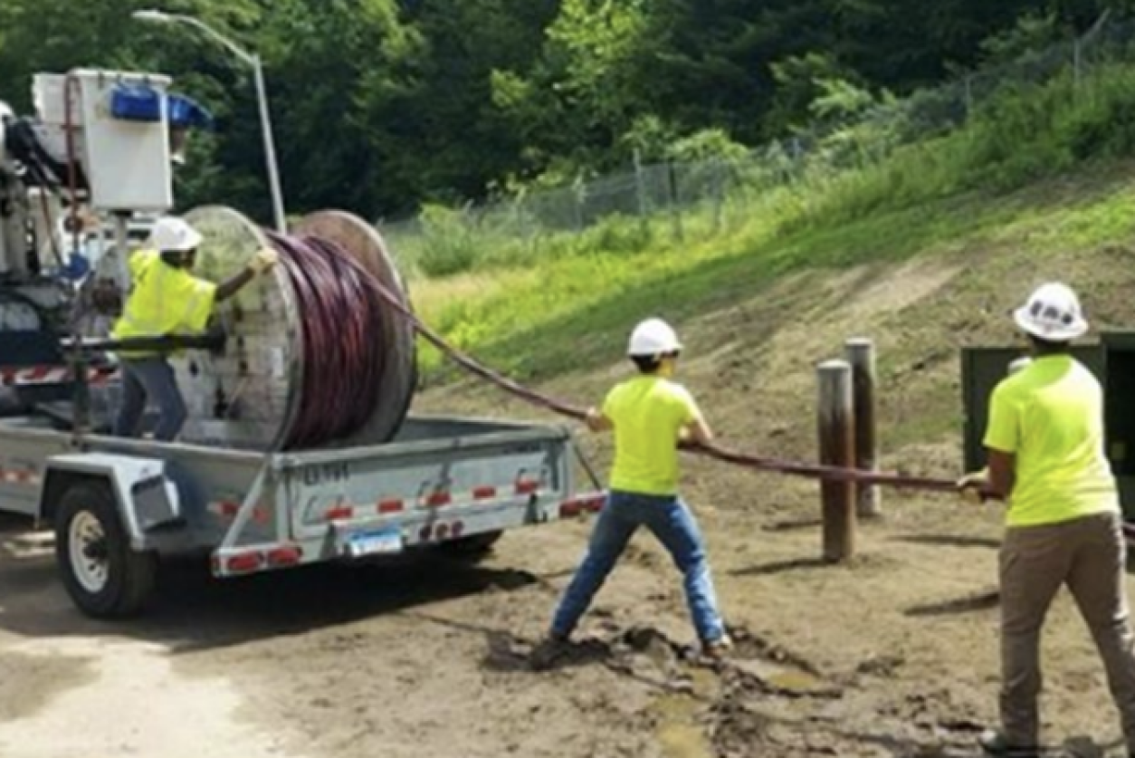 line workers pull line off truck.