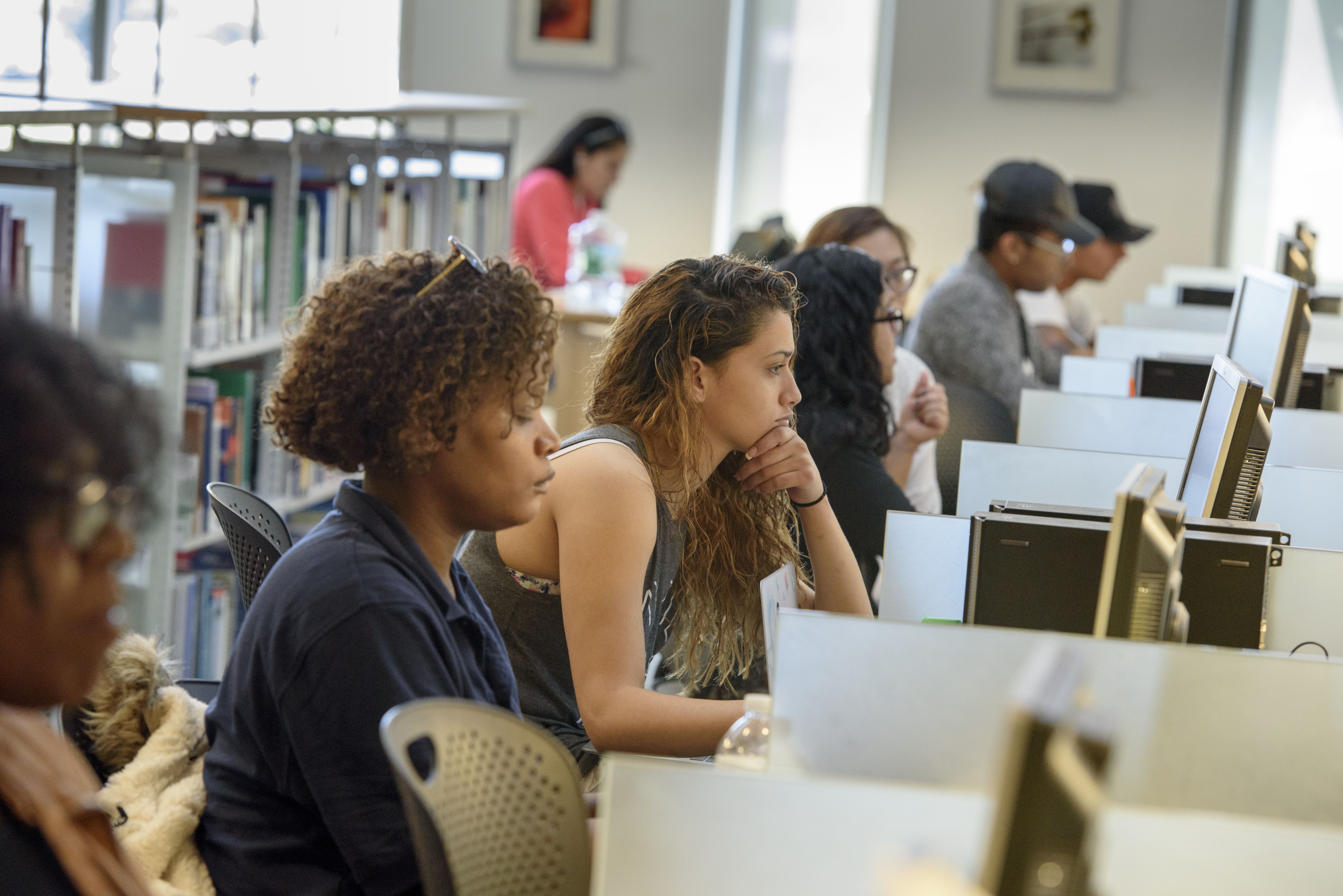 Students in library sitting in row of computers doing schoolwork