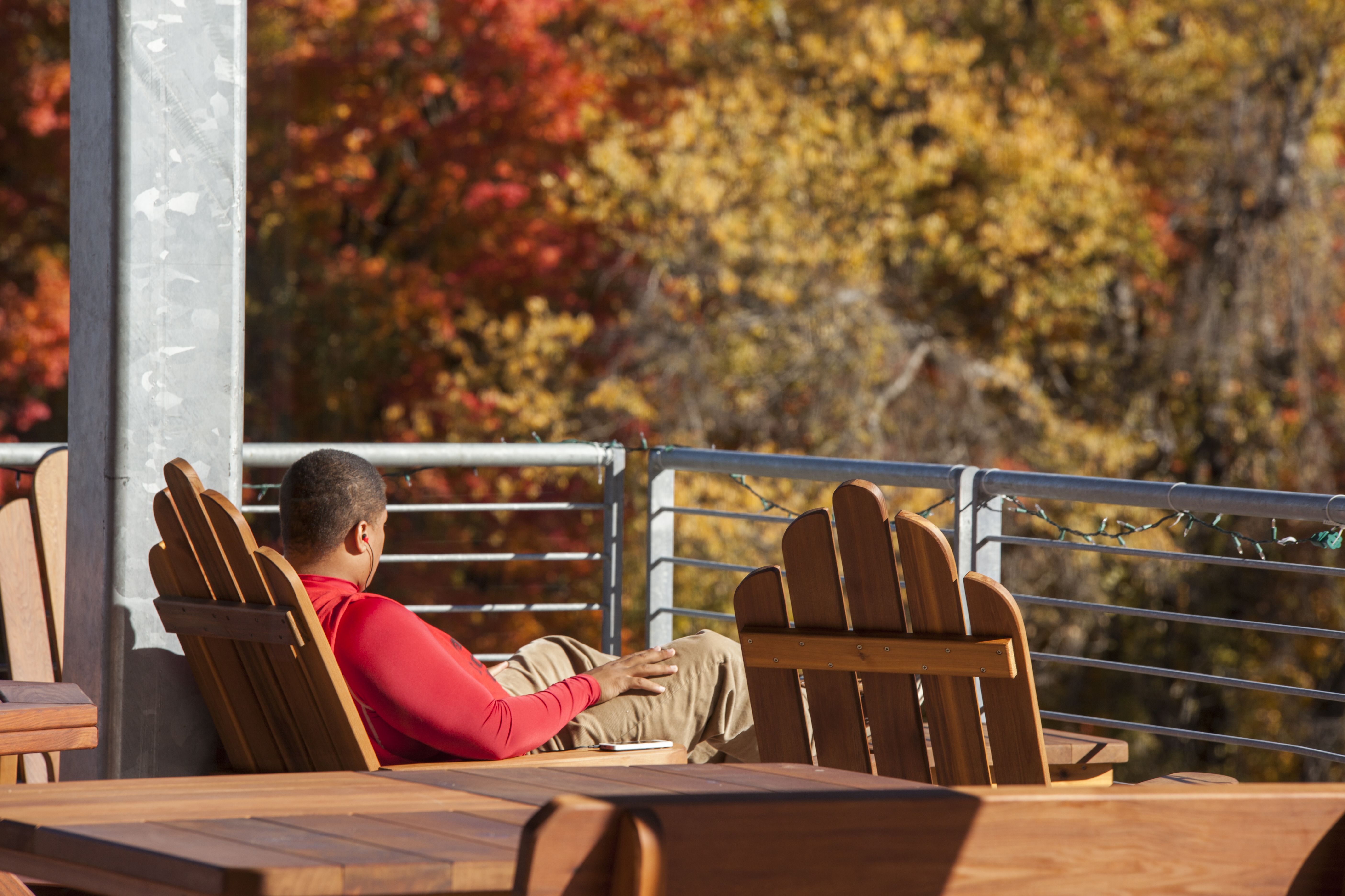 Student sits on pavilion deck looking out over the campus