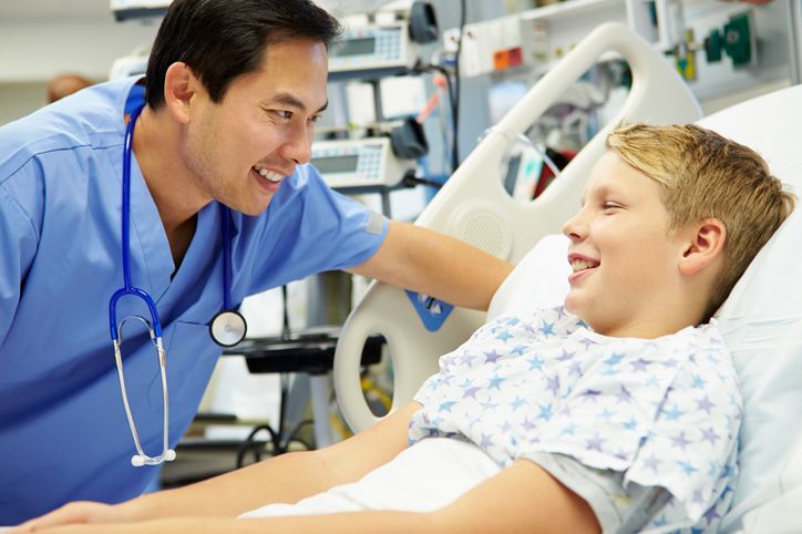 male nurse leans over young patient and they both smile