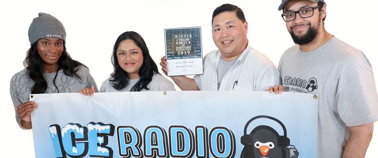 four students hold up ICE radio banner and one shows off award