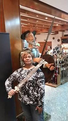 woman poses in front of statue with sword