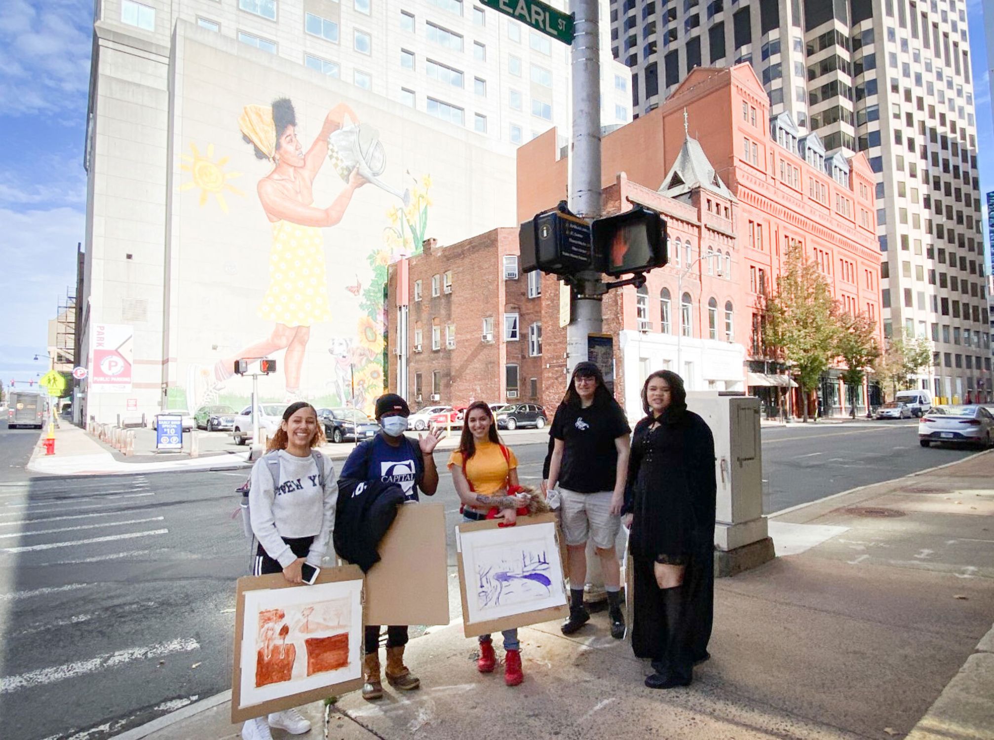 group of students holding artwork and bags stand outside of Capital