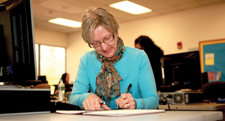 woman fills out notebook in computer lab