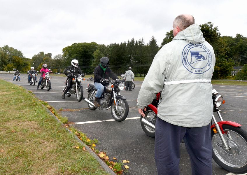 instructors stands in parking lot with riders on motorcycles lined up ready to go