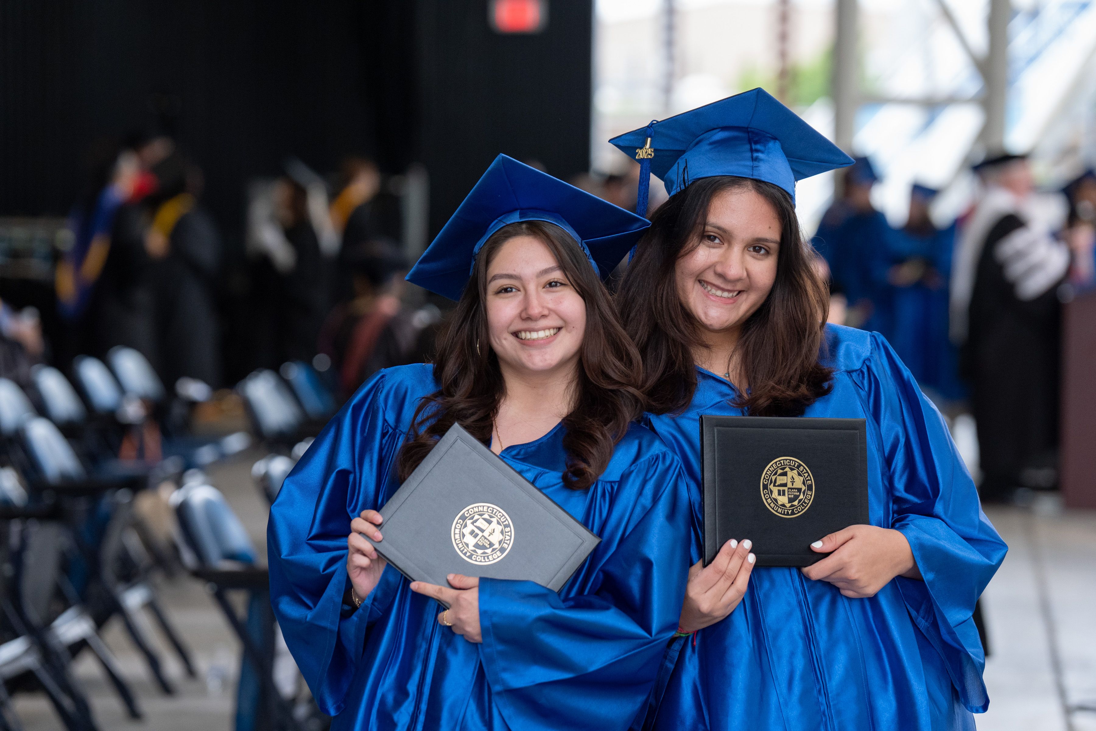 Students hold diplomas and smile at camera.