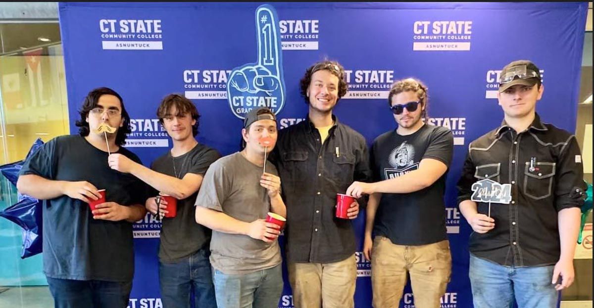Group stands in front of CT State backdrop at Asnuntuck Grad Fest