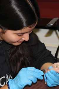 Esthetician student paints customer's nails