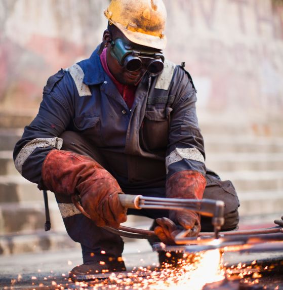 man squats and welds pipes