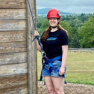 girl with harness and helmet prepares to climb 