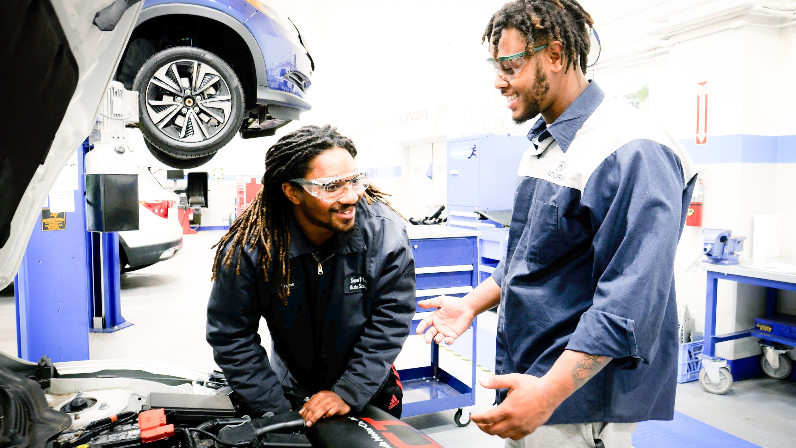 Two students in automotive shop work together