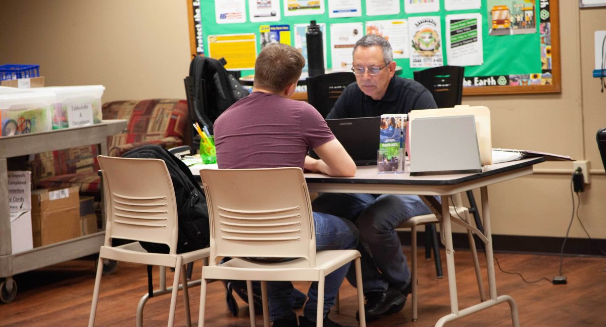 advisor and student talk over table to choose courses for upcoming semester