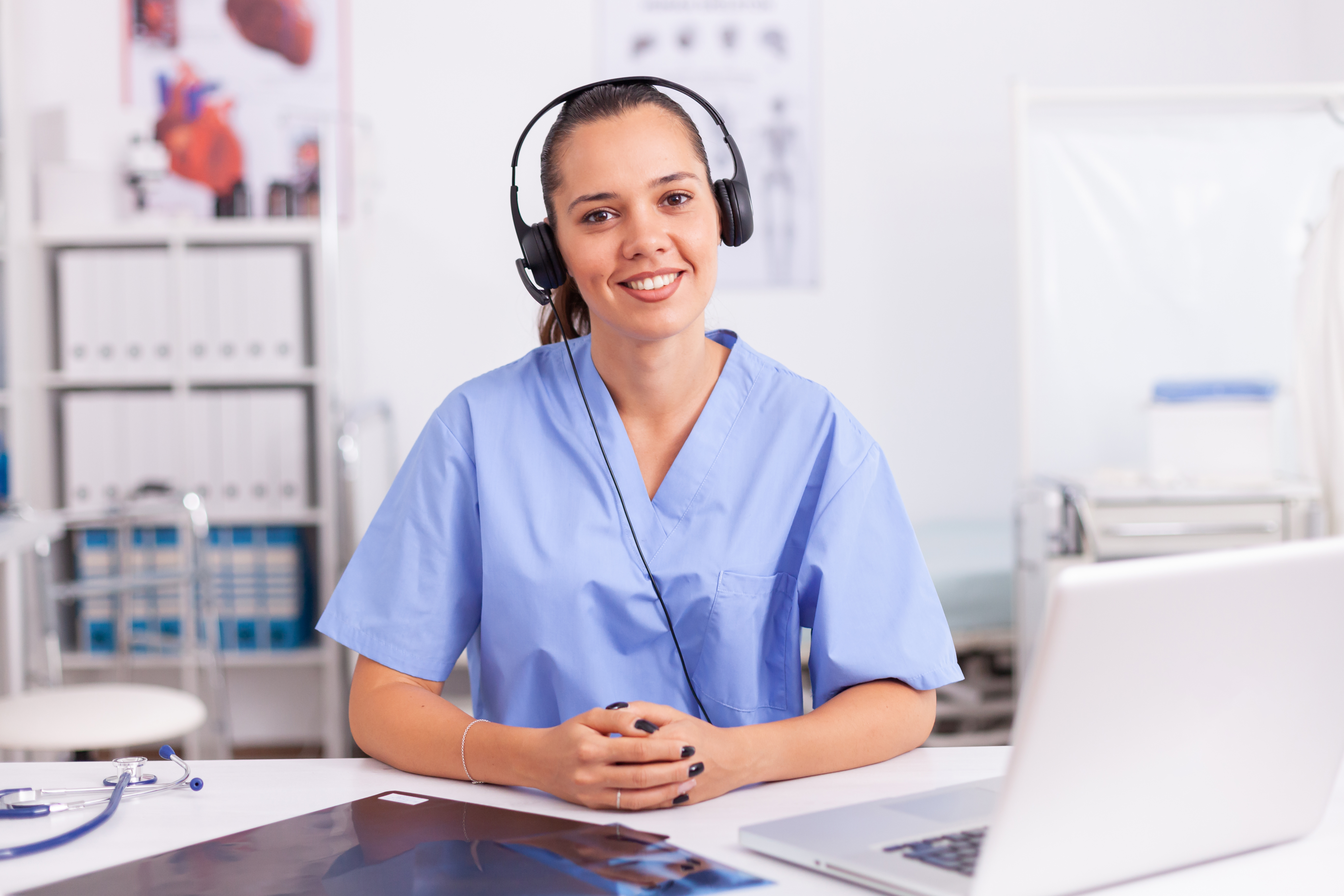 smiling medical assistant at computer with headset on